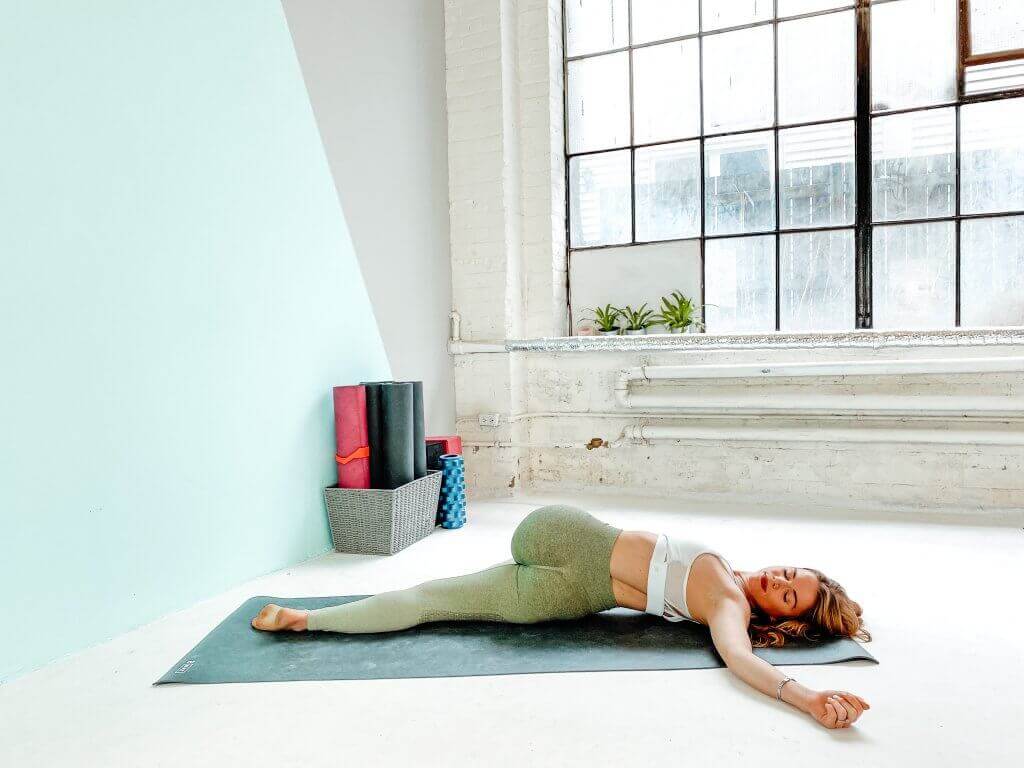Woman in a relaxing Supine Twist on her back.
