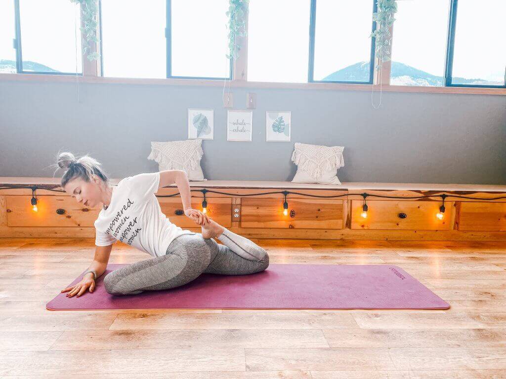 Woman in a deep pigeon pose with the back knee bent to intensify the quad stretch.