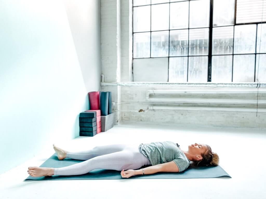 Woman lying in a final resting Corpse or Shavasana pose.