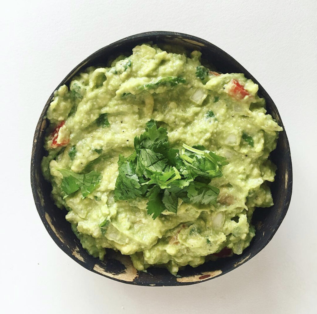 A bowl of freshly made guacamole with tortilla chips.